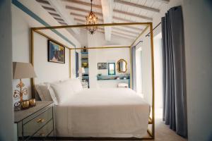 ein Schlafzimmer mit einem weißen Bett mit einem goldenen Rahmen in der Unterkunft Borgo 69 Villas & Suites in Foiano della Chiana