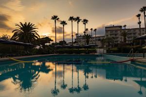a pool with palm trees and a sunset in the background at Kensington Resort Seogwipo in Seogwipo
