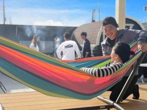 a man and a child laying in a hammock at itotoi 糸島 in Itoshima