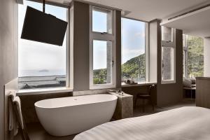 a bathroom with a tub and a tv and windows at Daybreak in Jiufen