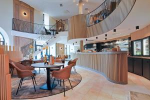 a restaurant with a table and chairs and stairs at Hotel Quartier Latin in Marche-en-Famenne