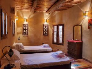 a bedroom with two beds and a mirror at Paloma Lodge in Siwa