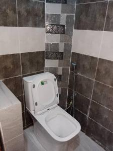 La salle de bains est pourvue de toilettes blanches et d'un mur carrelé. dans l'établissement Studio Emeraude - cosy et climatisé - Résidence Saraba Mermoz, à Dakar
