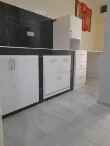 a kitchen with white cabinets and black counter top at Studio Emeraude - cosy et climatisé - Résidence Saraba Mermoz in Dakar