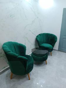 two green chairs and a table in a room at Studio Emeraude - cosy et climatisé - Résidence Saraba Mermoz in Dakar