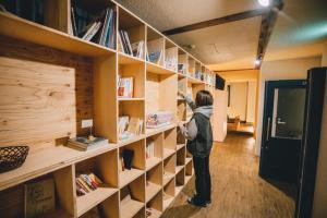 a woman is looking for books on a book shelf at Tug-B Bar & Hostel in Otaru