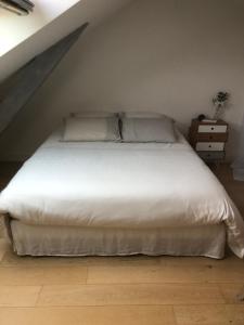 Schlafzimmer mit einem weißen Bett und Holzboden in der Unterkunft Jardin des Plantes in Le Mans