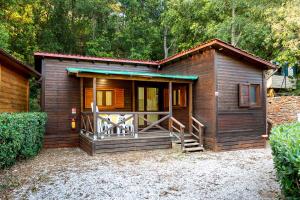 Cabaña de madera pequeña con porche y balcón en Elbadoc Camping Village, en Cavo
