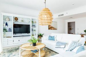 ein Wohnzimmer mit einem weißen Sofa und einem TV in der Unterkunft Luxurious 4 bed apartment on Yas Island, Abu Dhabi in Abu Dhabi