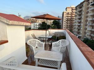 einen Balkon mit einem Tisch, Stühlen und einem Sonnenschirm in der Unterkunft Casa Rosina in Palermo