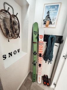 um par de esquis e snowboards pendurados numa parede em Maison de la montagne - Chambres & Jacuzzi em Arvier