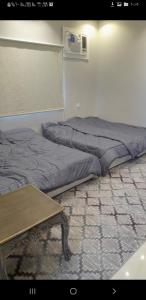 ein Schlafzimmer mit 2 Betten und einem Tisch auf dem Boden in der Unterkunft مزرعة الكرم الحاتمي in Al Shafa