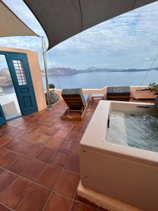 un patio con bañera de hidromasaje y vistas al agua en Horizon Aeifos Suites en Oia