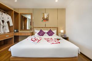 a bedroom with a large white bed with red flowers on it at Lavender Riverside Hotel in Da Nang