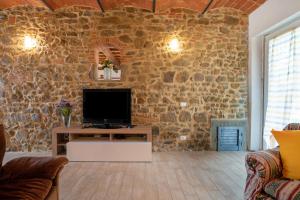 sala de estar con pared de piedra y TV de pantalla plana. en Casa I Pini, en Terranuova Bracciolini