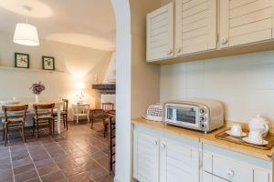 una cucina con forno a microonde e una sala da pranzo con tavolo di Sassi Scritti - Abete Bianco a Montefegatesi