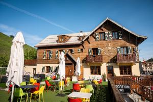 un restaurant avec des tables et des chaises en face d'un bâtiment dans l'établissement Hotel Le Blanche Neige, à Valberg