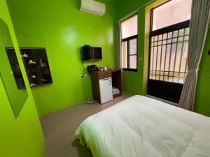 a green room with a bed and a small refrigerator at Chunfa B&B in Huxi