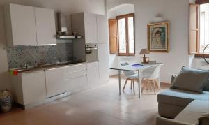 una cucina con armadi bianchi, tavolo e divano di Civico a Gubbio