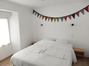 ein Schlafzimmer mit einem weißen Bett mit einem Banner an der Wand in der Unterkunft Le Cormoran emplacement idéal, moderne très équipé in Thury-Harcourt