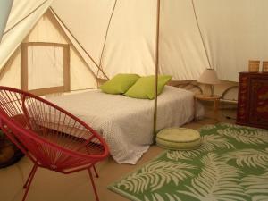 a bedroom with a tent with a bed and a chair at Camping du Petit Gué du Roi in Cléry-Saint-André