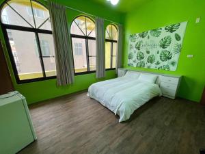 a green bedroom with a bed and two windows at Chunfa B&B in Huxi