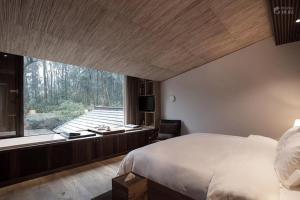 una camera con un grande letto e una grande finestra di Formeet Boutique Homestay a Hangzhou