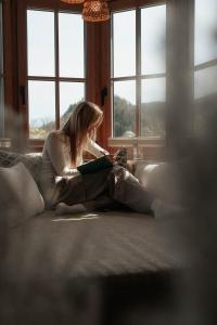 una mujer sentada en un sofá leyendo un libro en Bergrose Hideaway, en Strobl