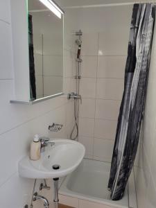 La salle de bains est pourvue d'un lavabo, d'un miroir et d'une baignoire. dans l'établissement Gästehaus Rosl, à Reifnitz