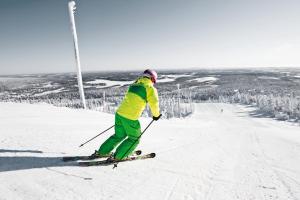 a person is skiing down a snow covered slope at Ski-Inn RukaSuites in Ruka