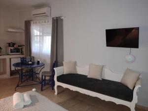 a living room with a bed and a table with a tv at Kampanelia Village Suites in Fira