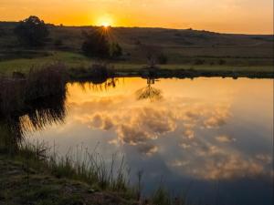 a reflection of the sun in the water at sunset at Kinloch Lodge in Dullstroom
