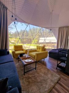 a living room with yellow furniture and a large window at Nomad Domes in Rugineşti