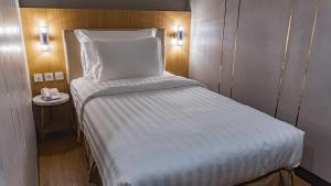 um pequeno quarto com uma cama branca e um telefone em d'primahotel Airport Jakarta Terminal 3 Wellness Center em Tangerang