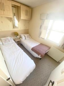 2 camas en una habitación pequeña con ventana en Seaside Holiday Home St. Osyth, Essex 2 Bathroom, 6 Berth with Country Views en Saint Osyth