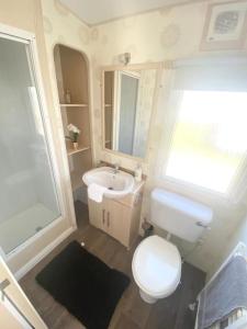 a bathroom with a white toilet and a sink at Seaside Holiday Home St. Osyth, Essex 2 Bathroom, 6 Berth with Country Views in Saint Osyth