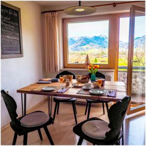 un tavolo da pranzo con sedie e una grande finestra di Wohnung Weitsicht a Ruhpolding