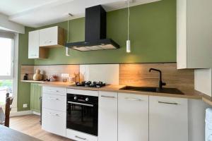 een keuken met witte kasten en groene muren bij L'Artistik - Appartement 5 min à pied du port et parking privé in Vannes