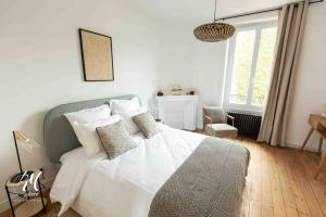 Schlafzimmer mit einem Bett mit weißer Bettwäsche und Kissen in der Unterkunft Les pierres blanches : T2 - Hypercentre Angoulême in Angoulême