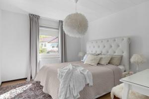 a white bedroom with a bed and a window at Modern and luxurious house -13 min by train from Gothenburg in Surte