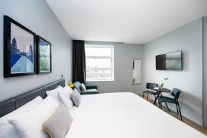 a bedroom with a large white bed and a table at Staycity Aparthotels London Greenwich High Road in London