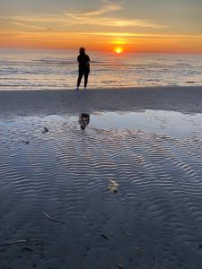 uma pessoa de pé na praia ao pôr do sol em Searooms Ragaciems em Ragaciems