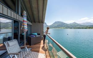 une femme debout sur un balcon donnant sur l'eau dans l'établissement Cortisen am See - Adults only, à Sankt Wolfgang im Salzkammergut