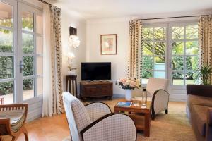 ein Wohnzimmer mit einem Sofa und einem TV in der Unterkunft Hostellerie De L'abbaye De La Celle - Teritoria in La Celle