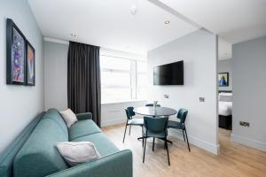 Staycity Aparthotels London Greenwich High Road في لندن: غرفة معيشة مع أريكة وطاولة