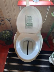 a toilet with the lid up in a bathroom at Stabbur Steinbekken, back to basic primitive overnight in Eidsvoll
