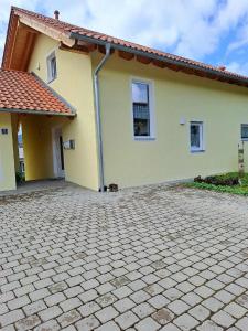 a yellow house with a brick driveway at Appartement Helga in Blaibach