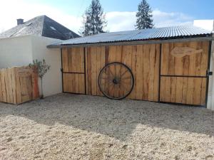 un cobertizo de madera con una rueda alrededor de una valla en L'aigrette moderne, ensoleillé et bien placé en Thury-Harcourt