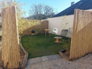 een tuin met twee houten hekken en een tafel en stoelen bij L'aigrette moderne, ensoleillé et bien placé in Thury-Harcourt