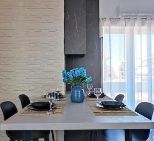 a dining room table with chairs and a blue vase with blue flowers at Margarita in Chania